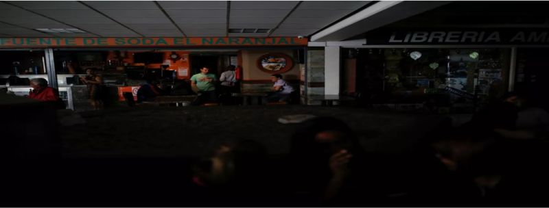 Pessoas conversam for a de restaurante atingido por apagão em Caracas, na Venezuela, nesta terça-feira (31) 