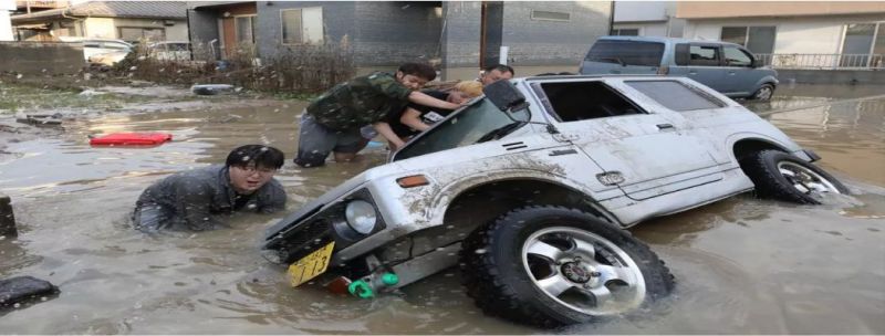 Moradores tentam erguer um veículo preso em uma área atingida pela enchente em Kurashiki, província de Okayama