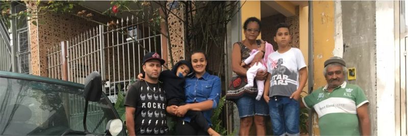 Leiliane posa ao lado da família na fachada da casa da mãe, em Pirituba, para onde se mudou após ser diagnosticada com doença rara
